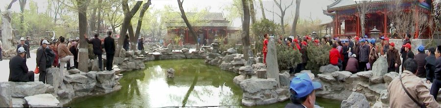 Chinese guide and crowds around a lake at Prince Gong's Residence