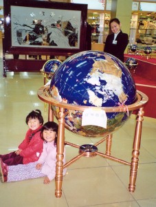 Cecilie and Yanmei sit and wait under the globe