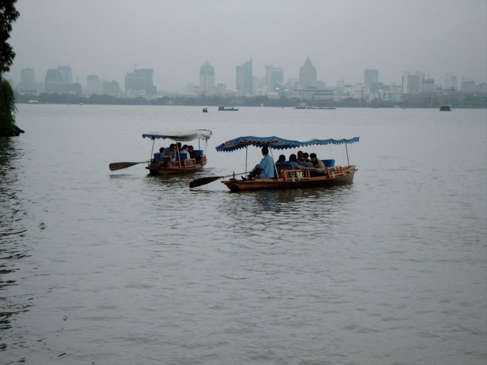 Row boats on the West Lake with the Hangzhou skyline in the background